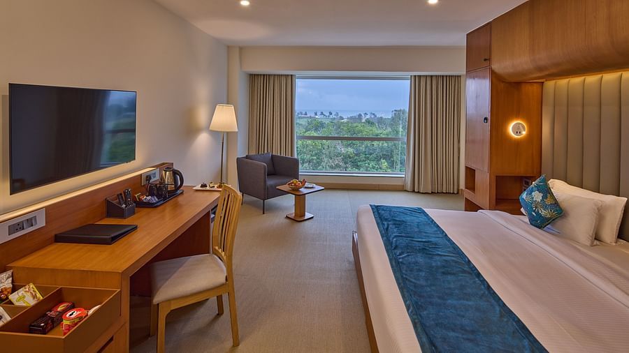a double bed, a sofa, a television, a desk and a chair in The Grand Premier King Sea View - Grand Continent, Mahabalipuram